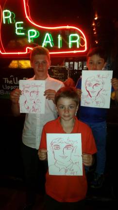 DRAWING INSPIRATION Daniel, 15; Fergus, 11; and Michael, 5, visitors from Ireland with portraits by Walter DeForest, aka #VGFY, who was making an attempt at a portrait-drawing record in preparation for his one-man show, “Van Gogh Find Yourself." Photo: #VGFY