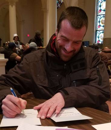 The Writing Den helps people in need connect Holy Apostles soup kitchen guest Peter, at The Writing Den’s December 2018 event, sent holiday cards to family members. Photo: Jill Higson