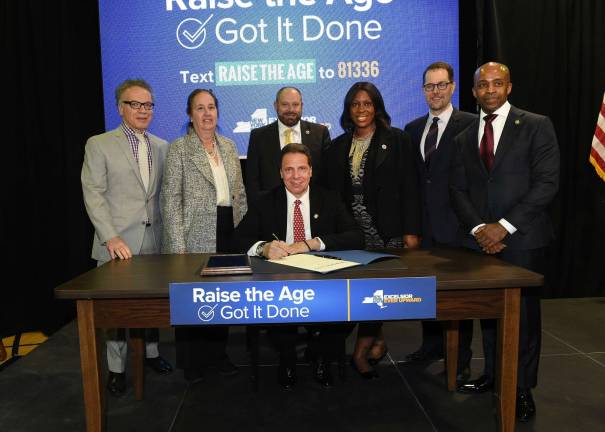 State budget passes, city’s in the works Flanked by supporters and several Manhattan elected officials, Gov. Andrew Cuomo signed legislation on Monday raising the age of criminality in New York from 16 to 18, which was approved when the state budget passed on Sunday. Photo: Kevin P. Coughlin/Office of the Governor