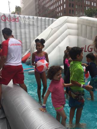 Children play in the wading portion of an inflatable waterpark on Park Avenue, part of the city's Summer in the Streets activities. Photo: Bryse Ciallella