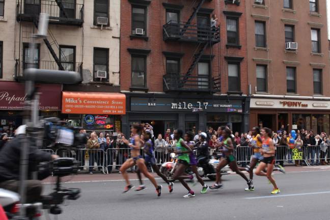 The first elite women racers run past Mile 17, a bar on First Avenue, during the early stages of the New York City Marathon Sunday. The bar, at the marathon's 17th mile, was filled with patrons throughout the race. Photo: Nomin Ujiyediin